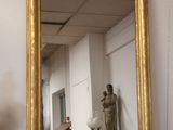 a gold framed mirror sitting on a table next to a vase