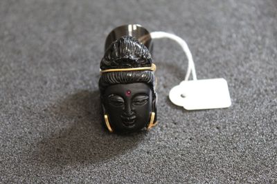 une petite statuette noire représentant Bouddha, à laquelle est attachée une étiquette