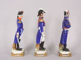 three figurines of men dressed in blue uniforms stand in front of a white background