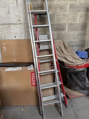 une échelle appuyée contre un mur, à côté d'une pile de cartons