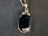 un collier orné d'une grosse pierre noire montée sur une chaîne en argent