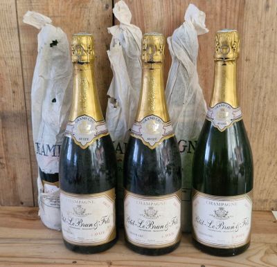 three bottles of champagne are lined up on a wooden table