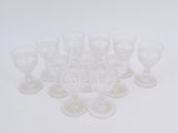 twelve clear glass cups and saucers arranged in a circle on a white surface