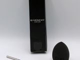 un gros plan d'une éponge de maquillage noire à côté d'un pinceau noir