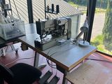 a desk with a sewing machine and a chair in front of a window