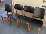 four black leather chairs are lined up against a wall in a parking lot