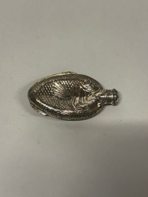 une assiette en argent décorée d'un poisson, posée sur une table
