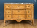 une commode ancienne avec un plateau en marbre posée sur un parquet