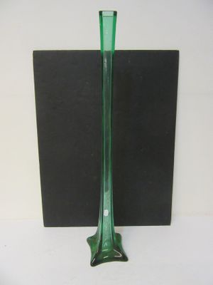 un vase en verre vert posé sur une surface noire