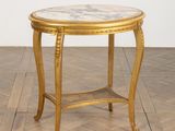 une table dorée avec un plateau en marbre posée sur un parquet