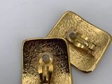 two gold metal buttons on a white surface with a white background