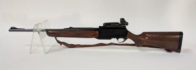 un fusil sur fond blanc, posé dans un support en plastique transparent