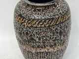un vase noir et or posé sur une surface blanche
