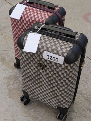 two pieces of luggage with tags on them sitting on the ground