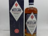 une bouteille de whisky Westland posée à côté d'une boîte sur une table