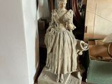 une statue de femme assise sur une table à côté d'une horloge