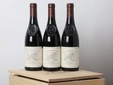 trois bouteilles de vin rouge dans une caisse en bois posée sur une table
