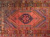 un vieux tapis persan aux motifs colorés sur fond rouge
