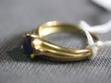 a gold ring with a blue stone on a white string