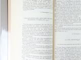 an open book on a table with a cat sitting on top of it