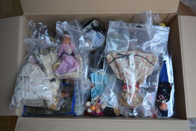 a cardboard box filled with assorted dolls and other items