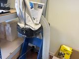 a computer on a desk with a vacuum in the corner of the room