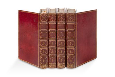 trois livres en cuir rouge sont empilés les uns sur les autres sur une surface blanche