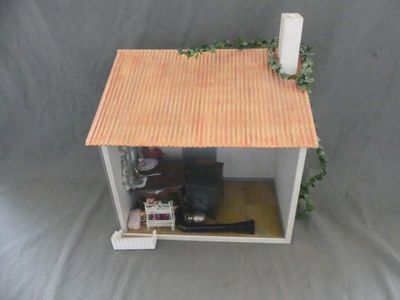 une petite maison de poupées avec un toit rouge et un toit marron