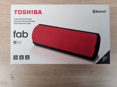 La boîte est ouverte sur une table sur laquelle se trouve un haut-parleur rouge.