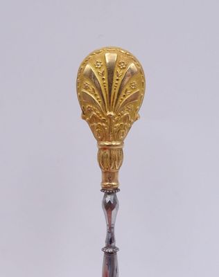 une image représentant une cuillère en or et une cuillère en argent posées sur une surface blanche