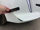 a hand that is holding a remote control near a white car
