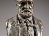 a bronze bust of a man with a beard and a bow tie