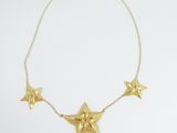 a close up of a gold necklace with five stars on it
