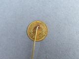 someone is holding a pin with a gold coin on it