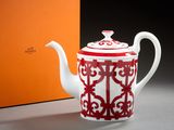 une théière rouge et blanche posée à côté d'une boîte orange