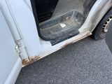 a white truck with a dirty door on the side of the road
