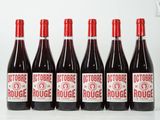 six bouteilles de vin rouge sont alignées sur une table