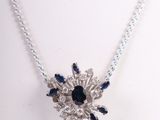 a close up of a necklace with blue and white stones on a white mannequin