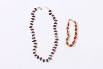 two necklaces and a bracelet on a white surface