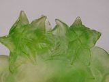 un gros plan d'un objet en verre vert posé sur une surface blanche