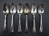 six spoons are lined up in a row on a black surface