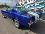 une photo d'une Mustang bleue garée devant un panneau