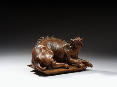 sculpture en bronze représentant un taureau couché sur un morceau de bois