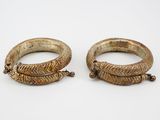 a pair of gold bracelets on a white surface