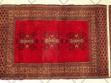 Le tapis posé au sol est rouge et marron et comporte un motif.