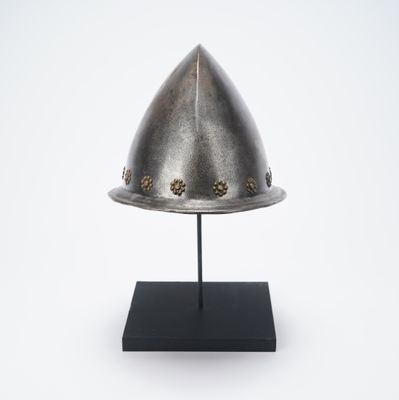 an antique helmet on a black stand on a white background