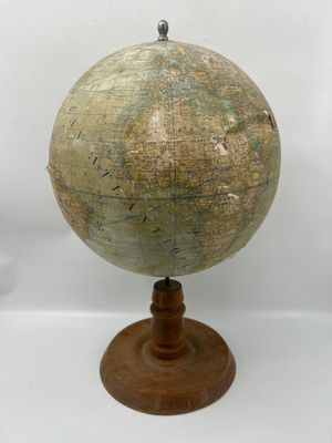 un vieux globe terrestre posé sur un socle en bois, sur fond blanc
