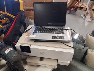 a laptop sitting on top of a printer on a table