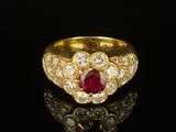 a close up of a gold ring with a ruby and diamond center