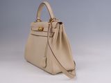 a close up of a beige handbag on a white surface